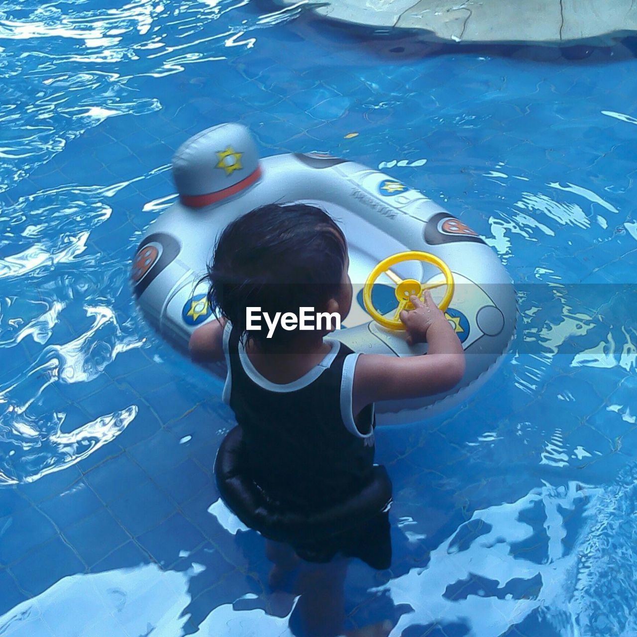 REAR VIEW OF MAN SWIMMING IN POOL