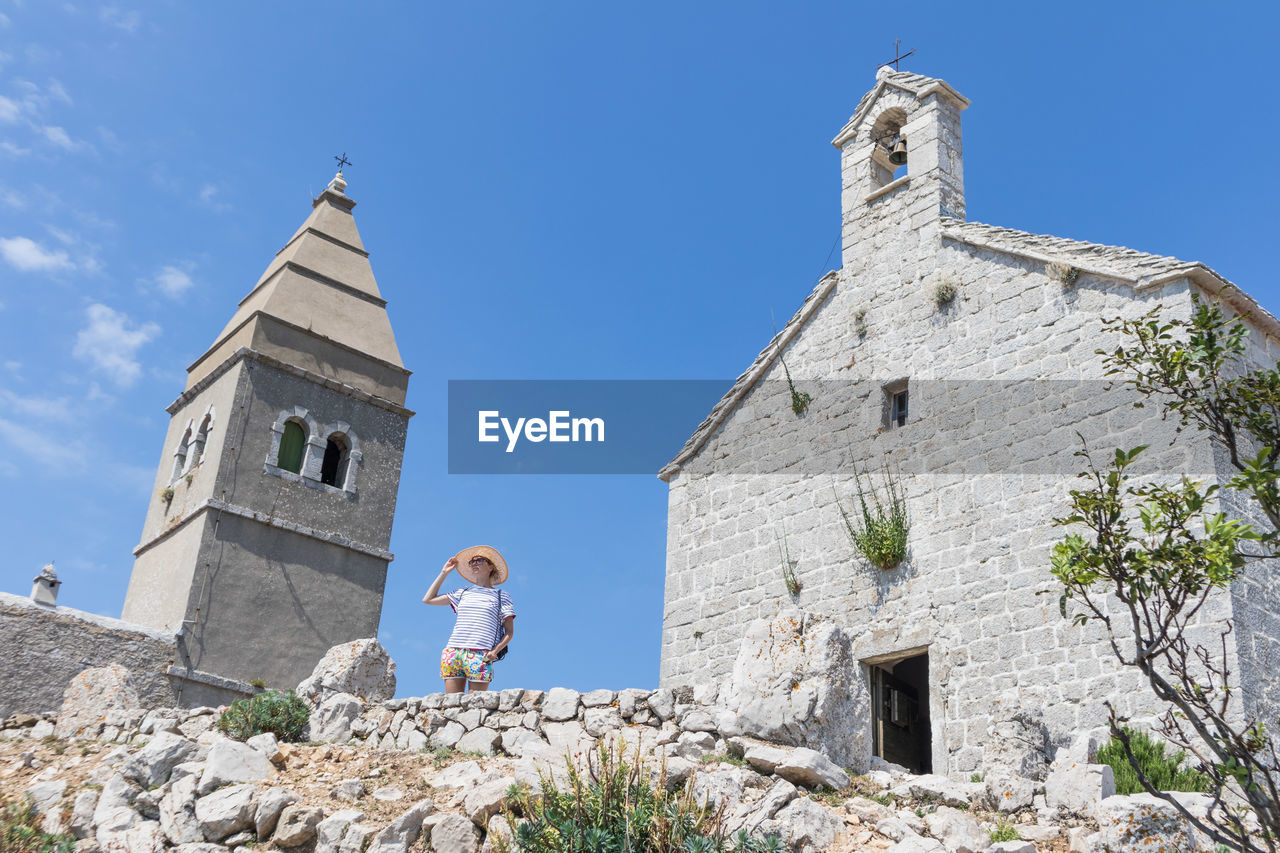 Low angle view of woman by historic building against sky