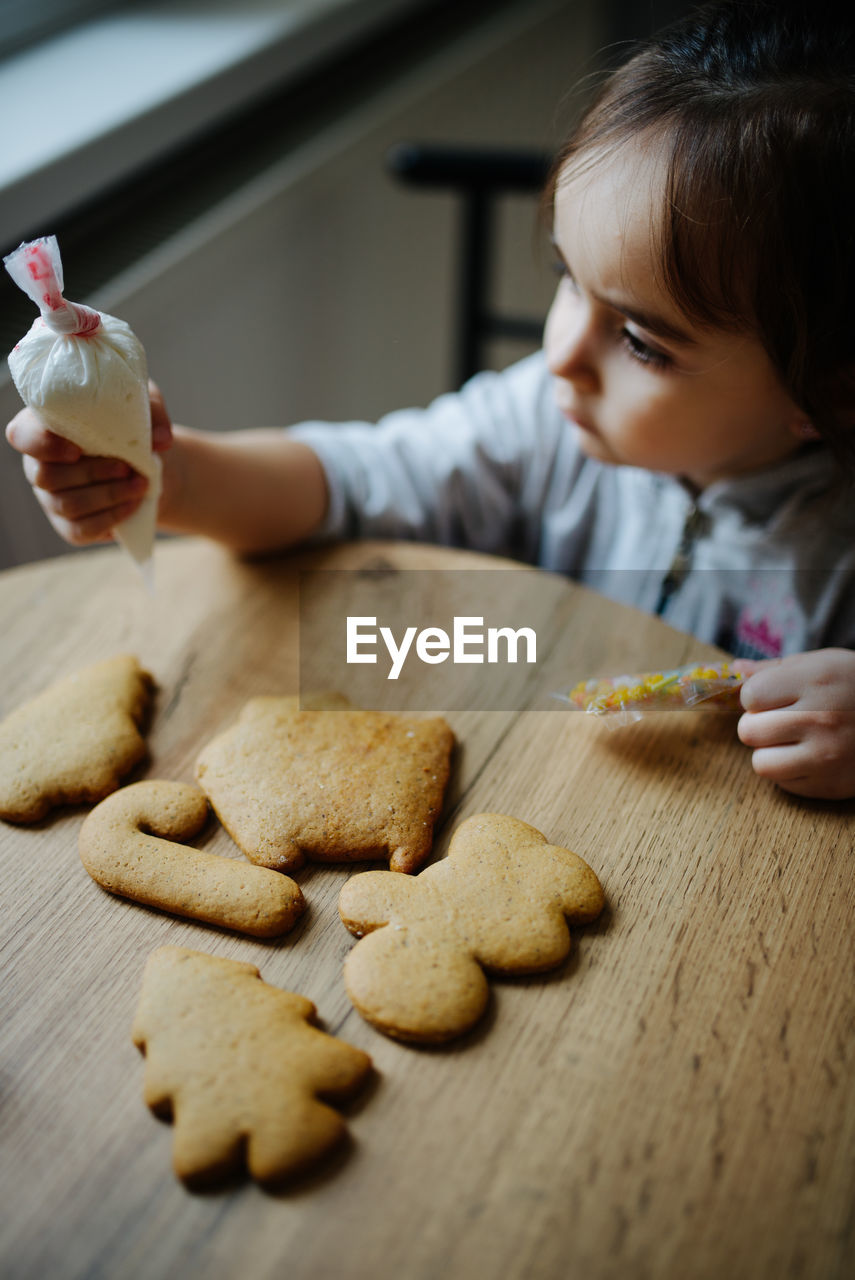 Little girl holding cream in a bag for cookie decoration .