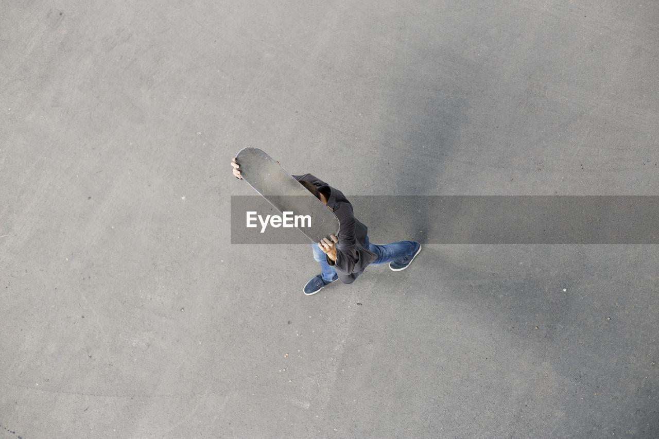 High angle view of man with skateboard walking on road