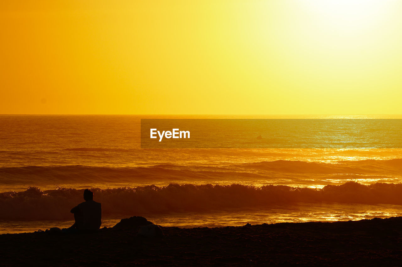Silhouette woman looking at sea against sky during sunset