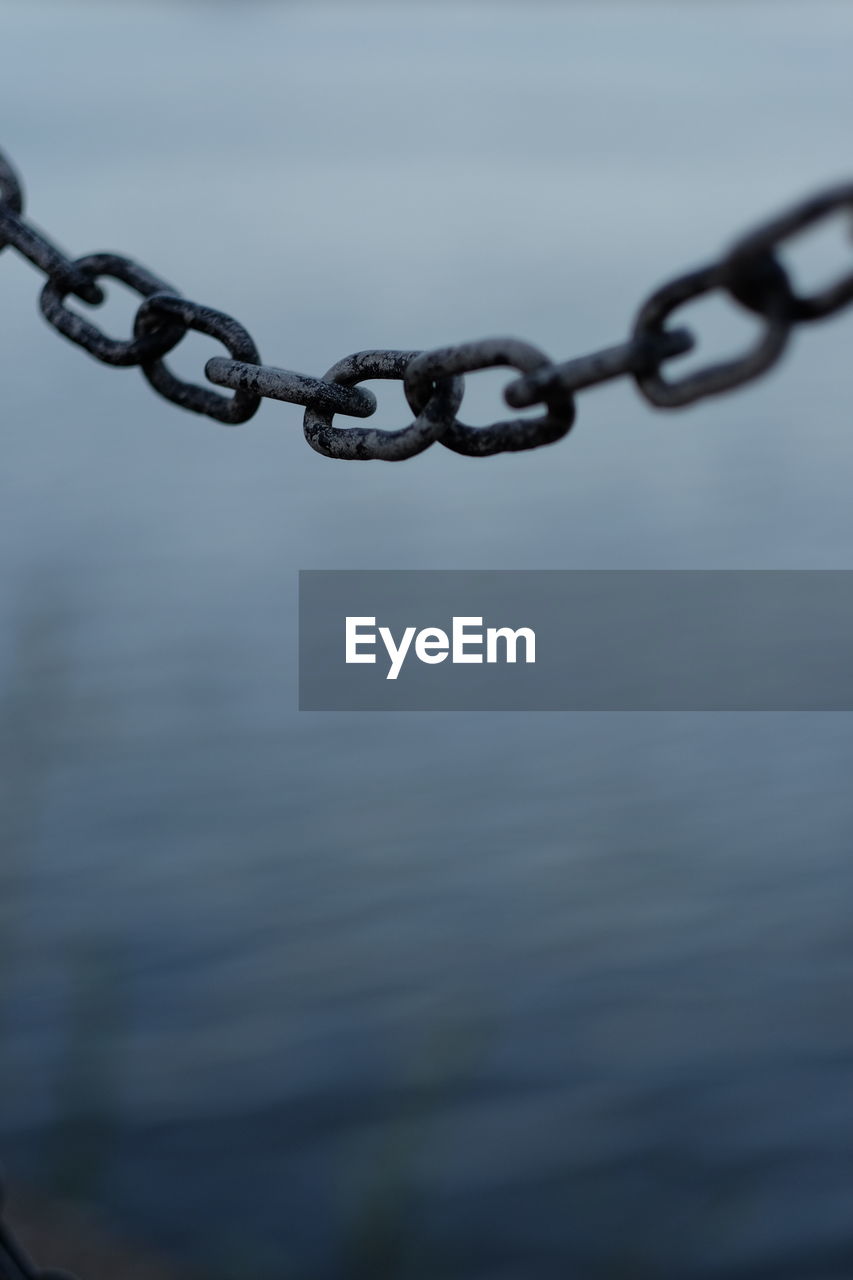 Close-up of chain hanging against sea