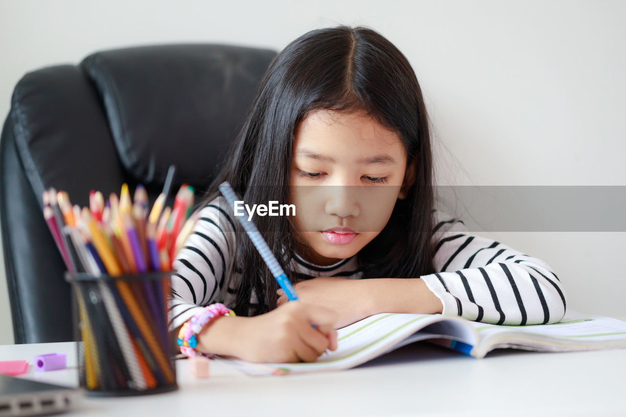 YOUNG WOMAN SITTING ON TABLE WITH BOOK