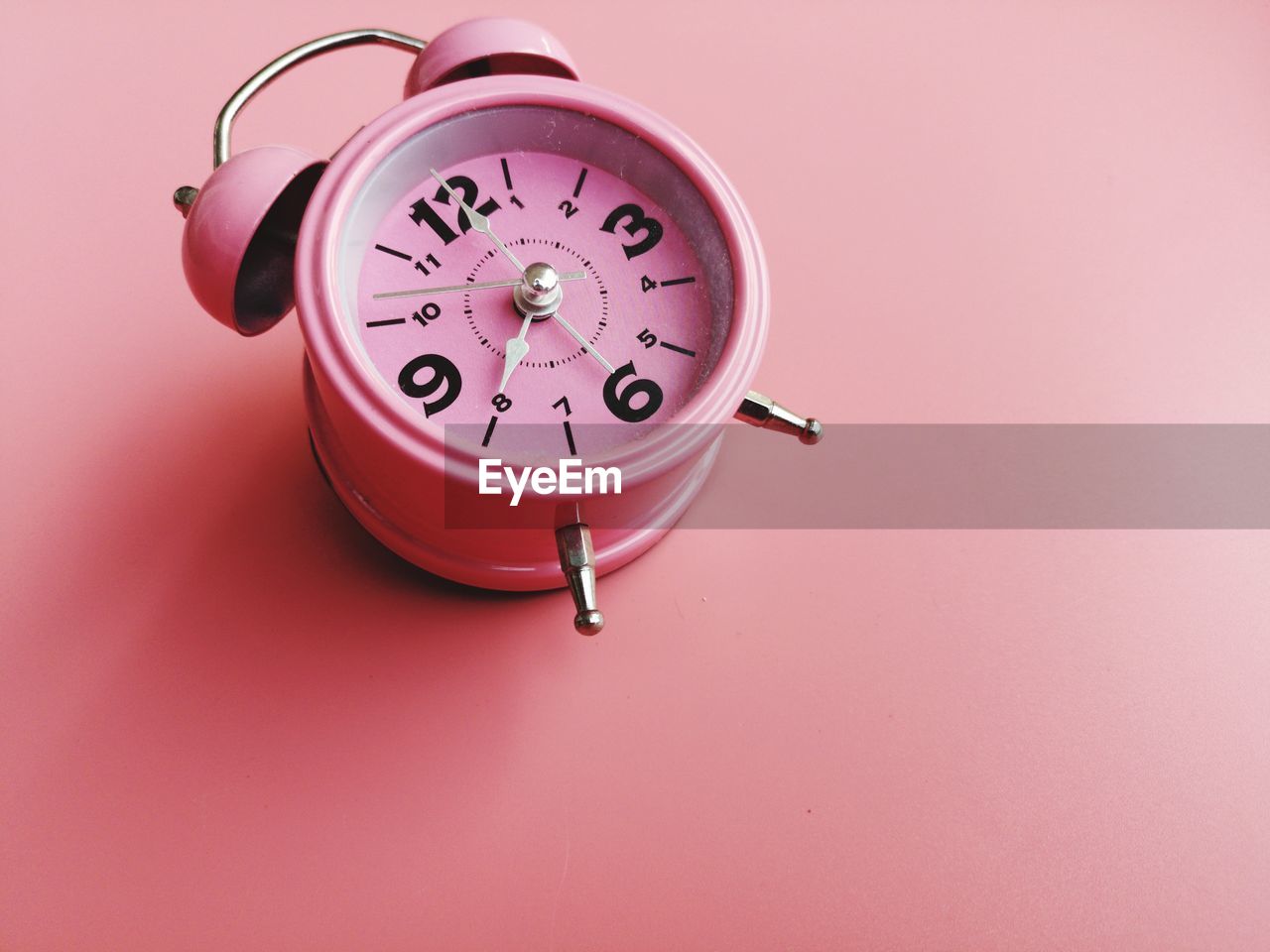 High angle view of alarm clock on pink background