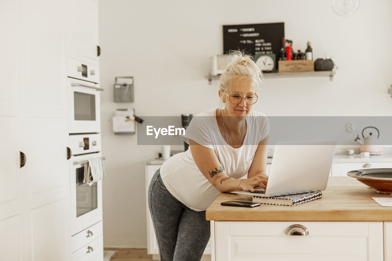 Woman using laptop in kitchen