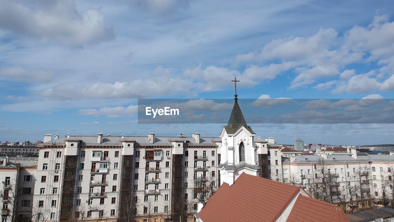 Buildings in city against cloudy sky