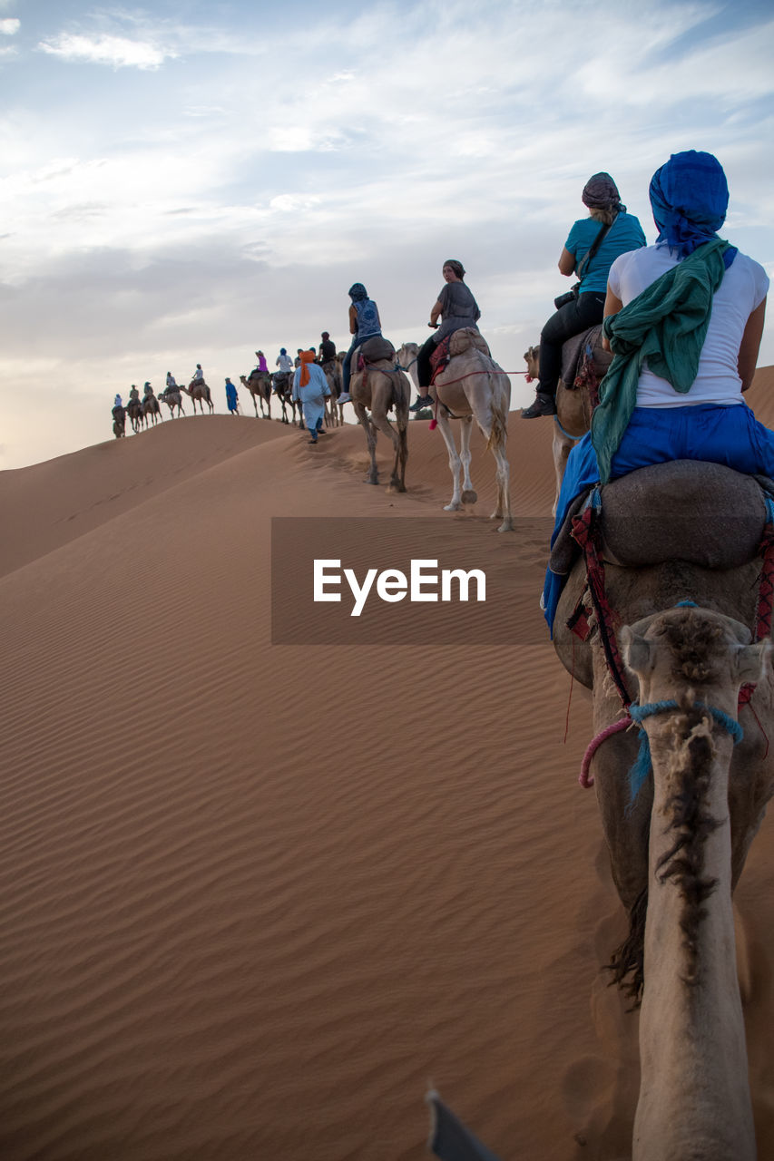 GROUP OF PEOPLE RIDING ON SAND