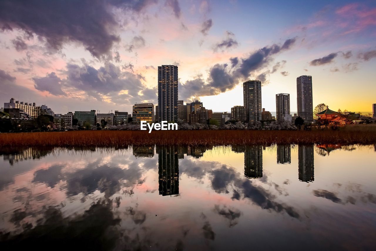 REFLECTION OF BUILDINGS ON LAKE AGAINST SKY