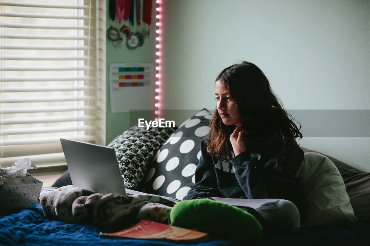 Tween girl looking at her laptop screen during a zoom class meeting