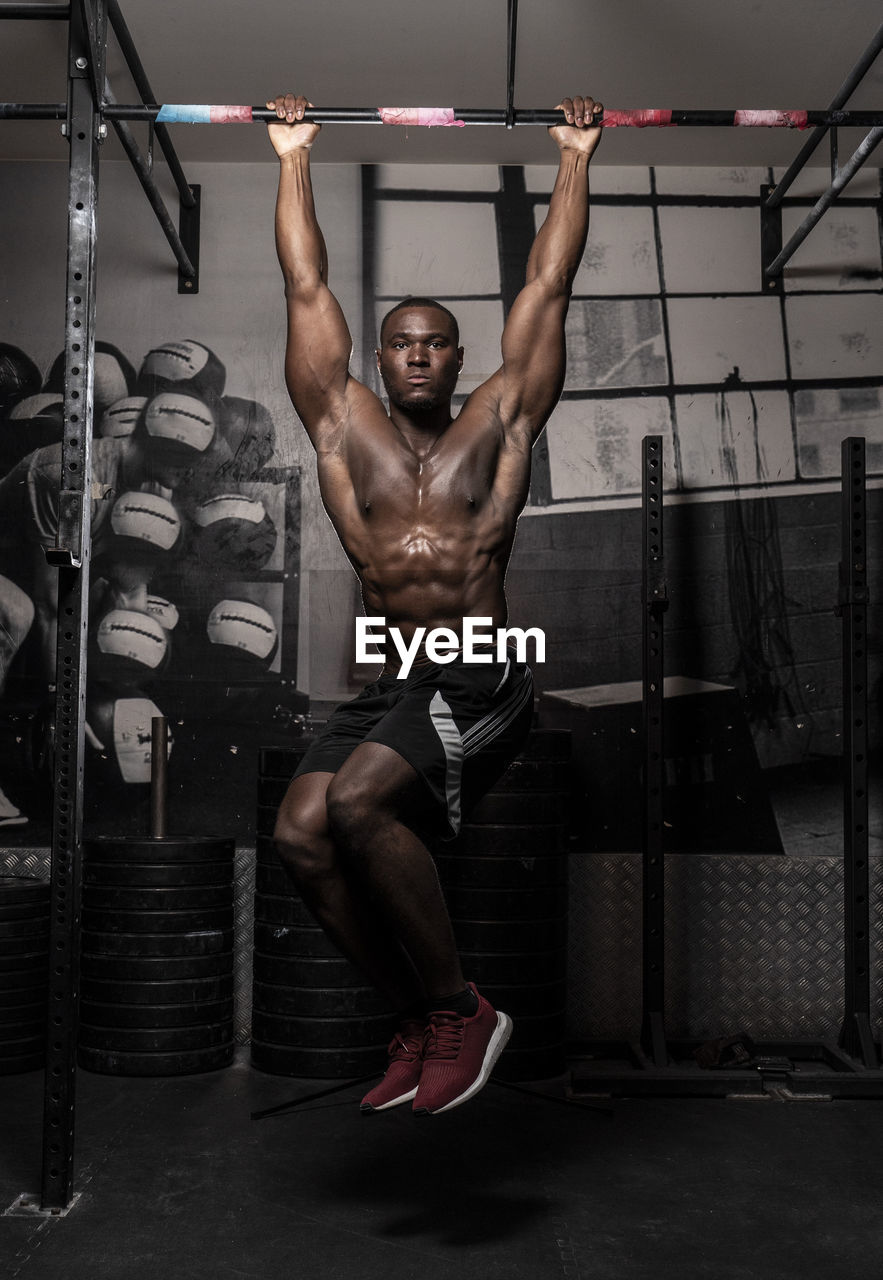 FULL LENGTH OF SHIRTLESS YOUNG MAN WITH ARMS OUTSTRETCHED