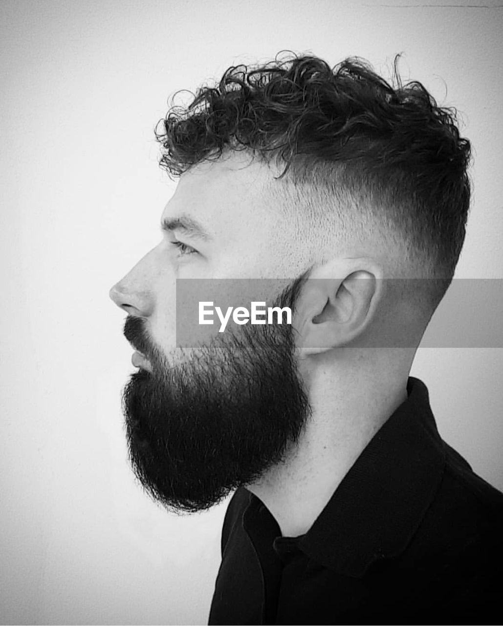 Profile view of young man with beard against gray background