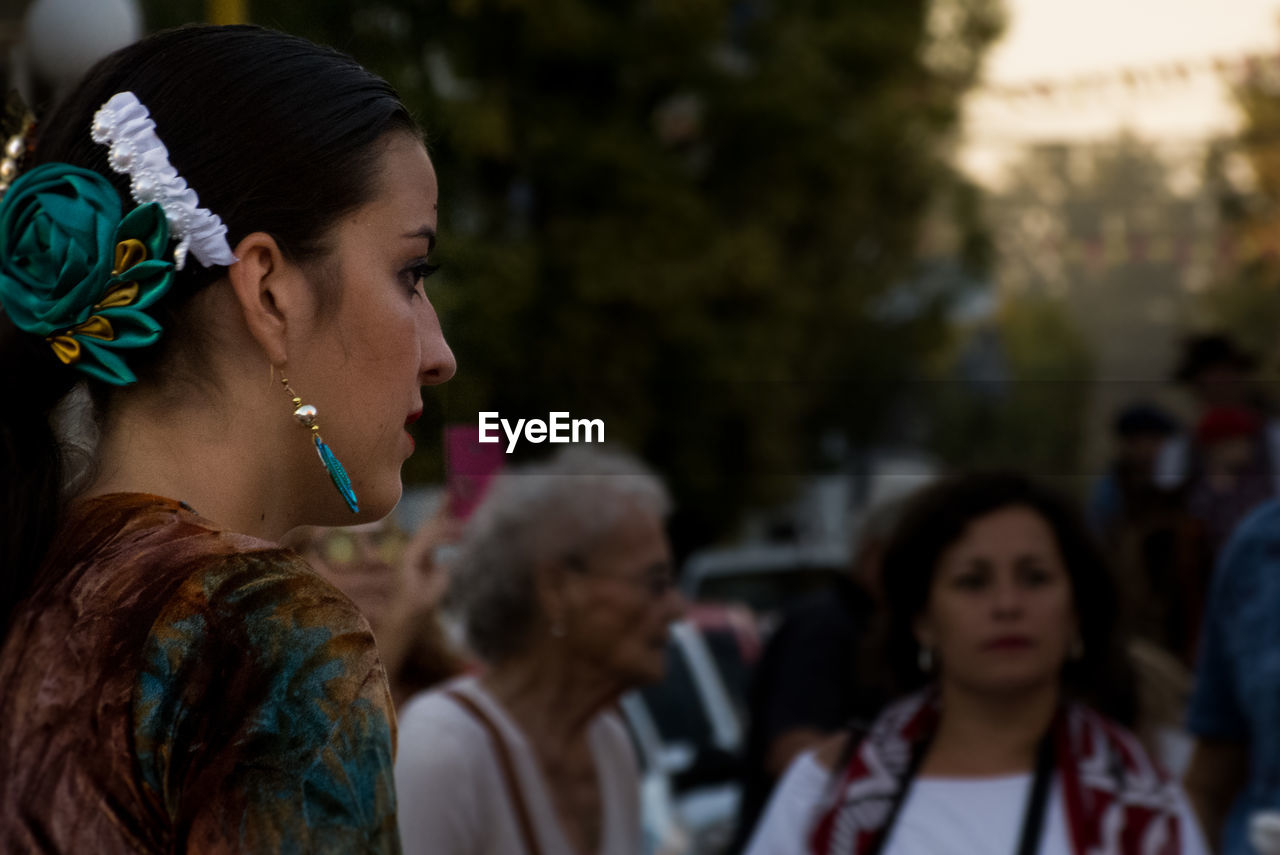 Side view of young woman wearing earring and hair accessory outdoors