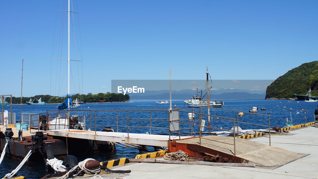 SAILBOATS MOORED ON SEA AGAINST CLEAR SKY