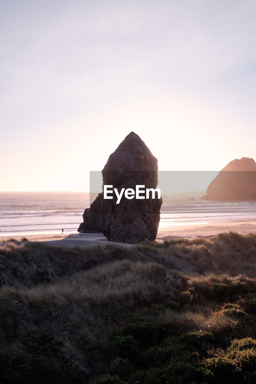 Rock formation on beach against sky during sunset