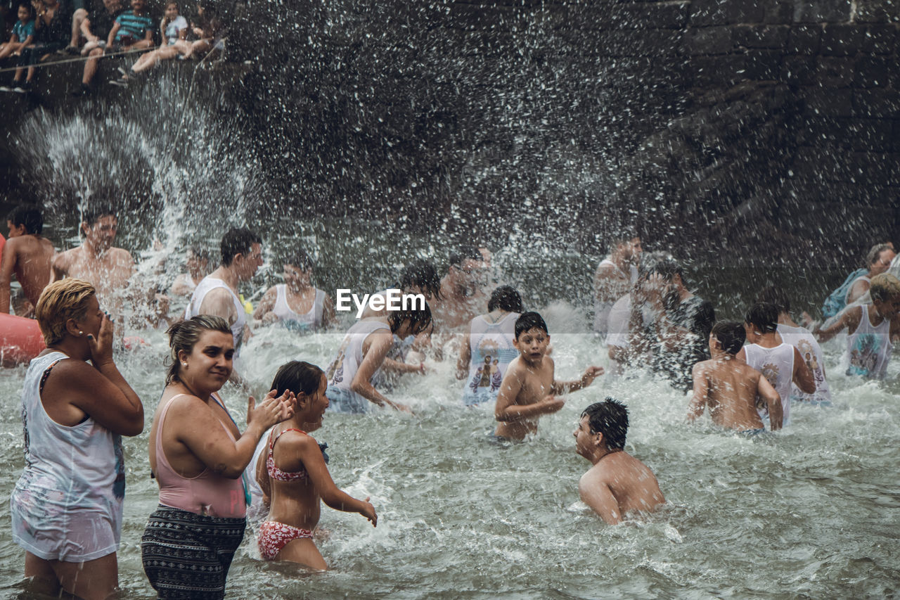 GROUP OF PEOPLE ENJOYING IN WATER AT NIGHT