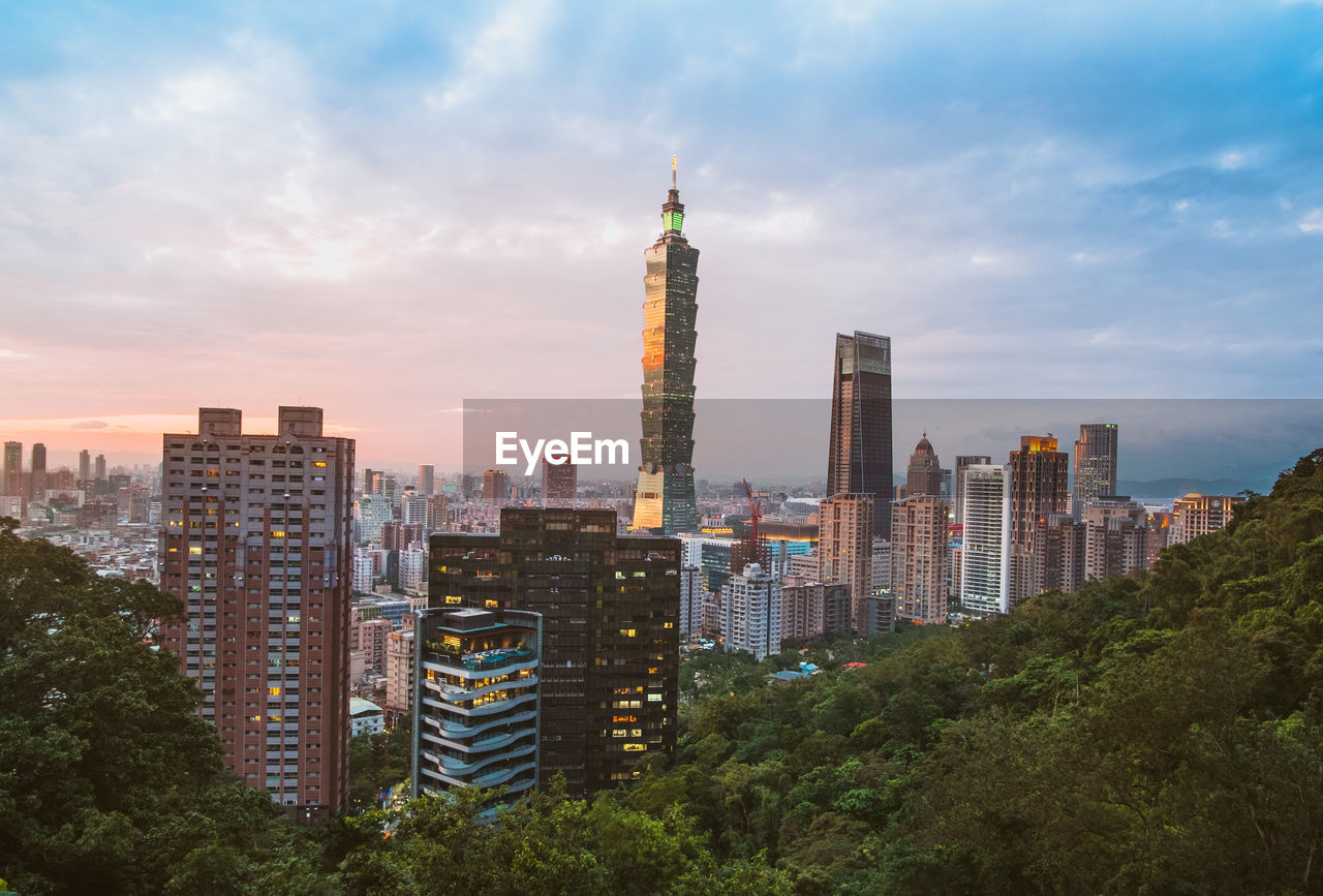 Modern buildings in city against cloudy sky during sunset