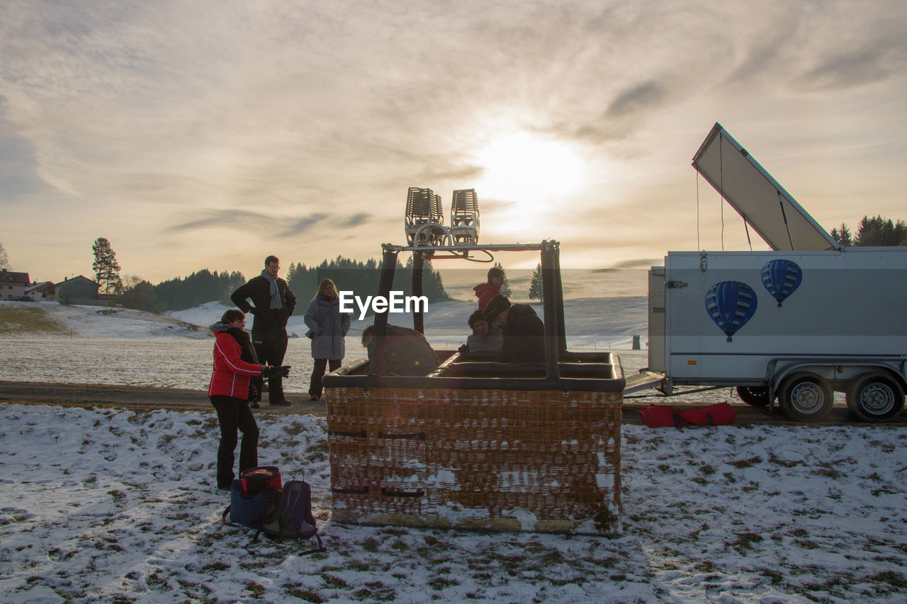 PEOPLE ON BEACH DURING WINTER AGAINST SKY