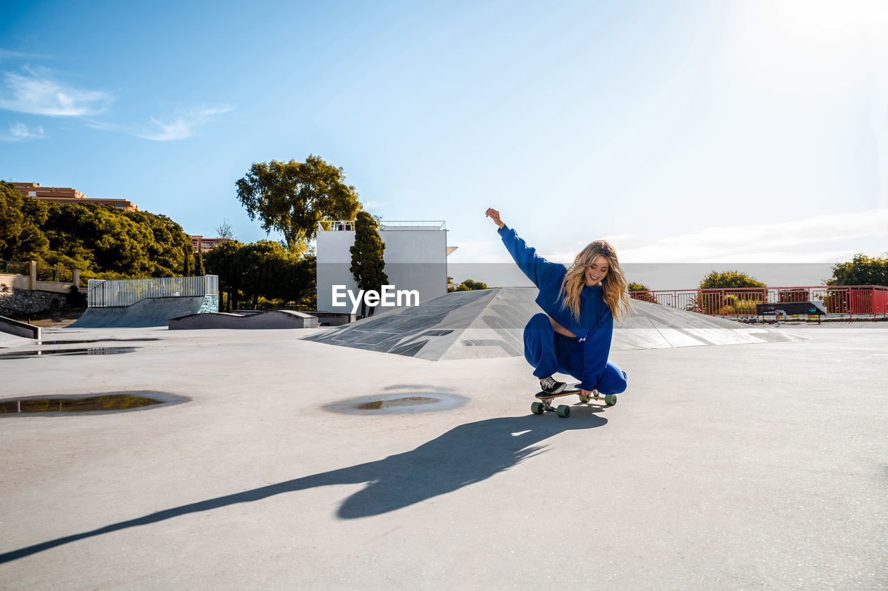 Cheerful caucasian woman with blonde hair skating in urban setting