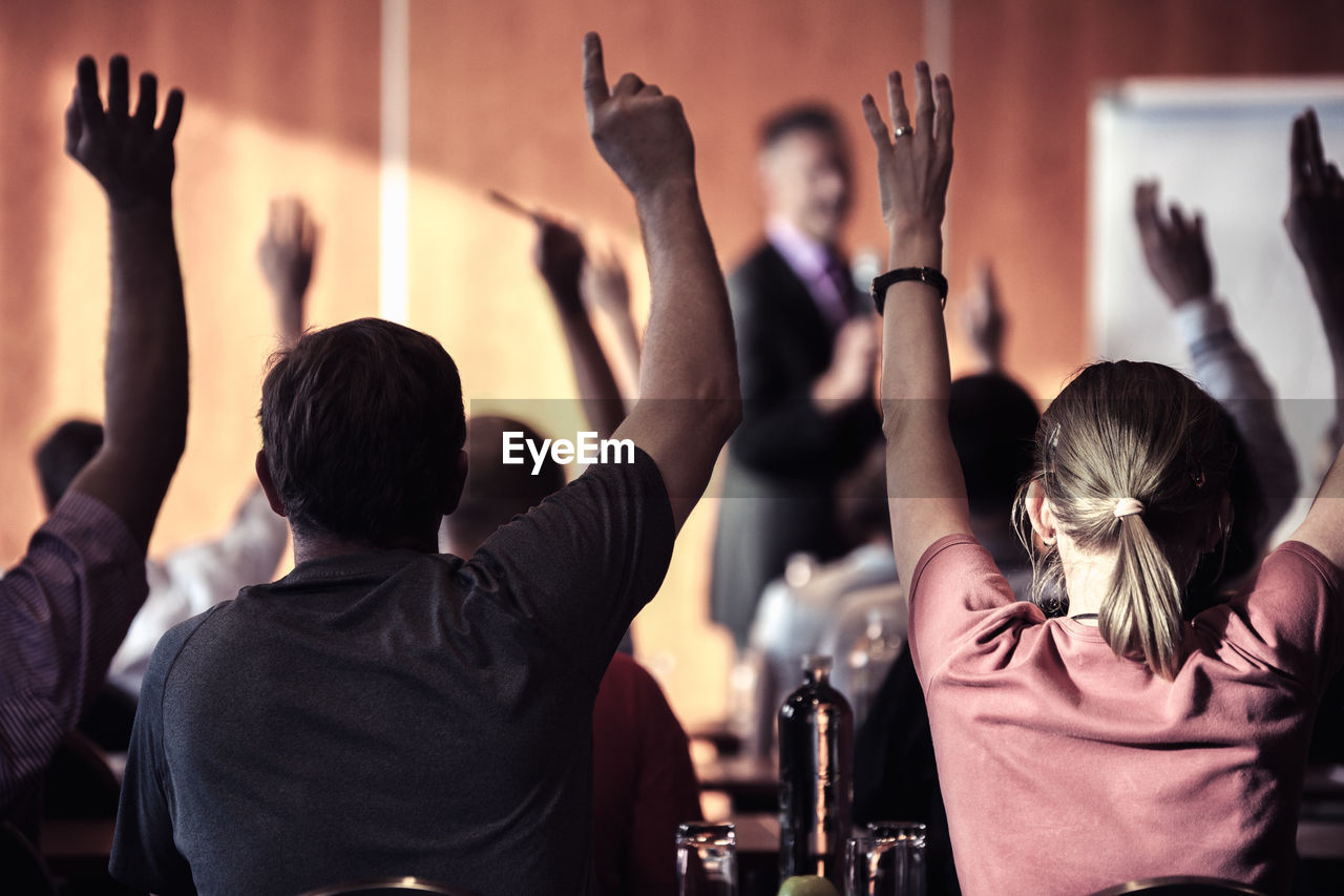 Audience with arms raised in lecture hall during seminar