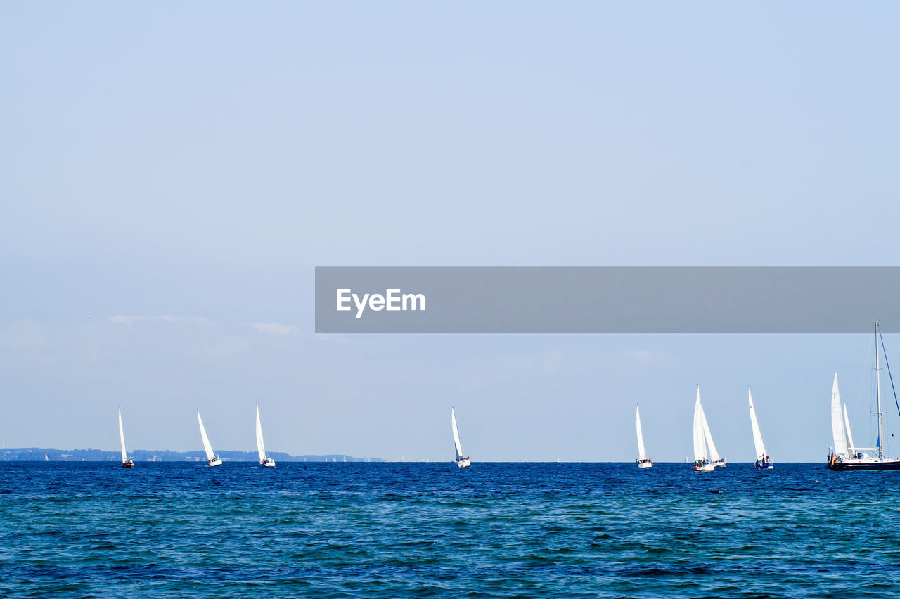 Sailboats in sea against sky