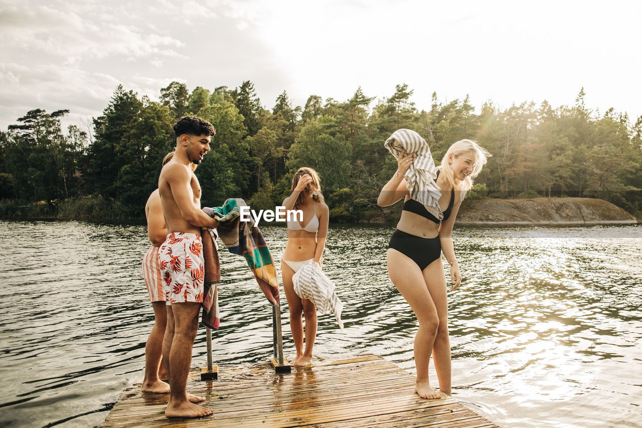 Male and female friends enjoying by lake during vacation