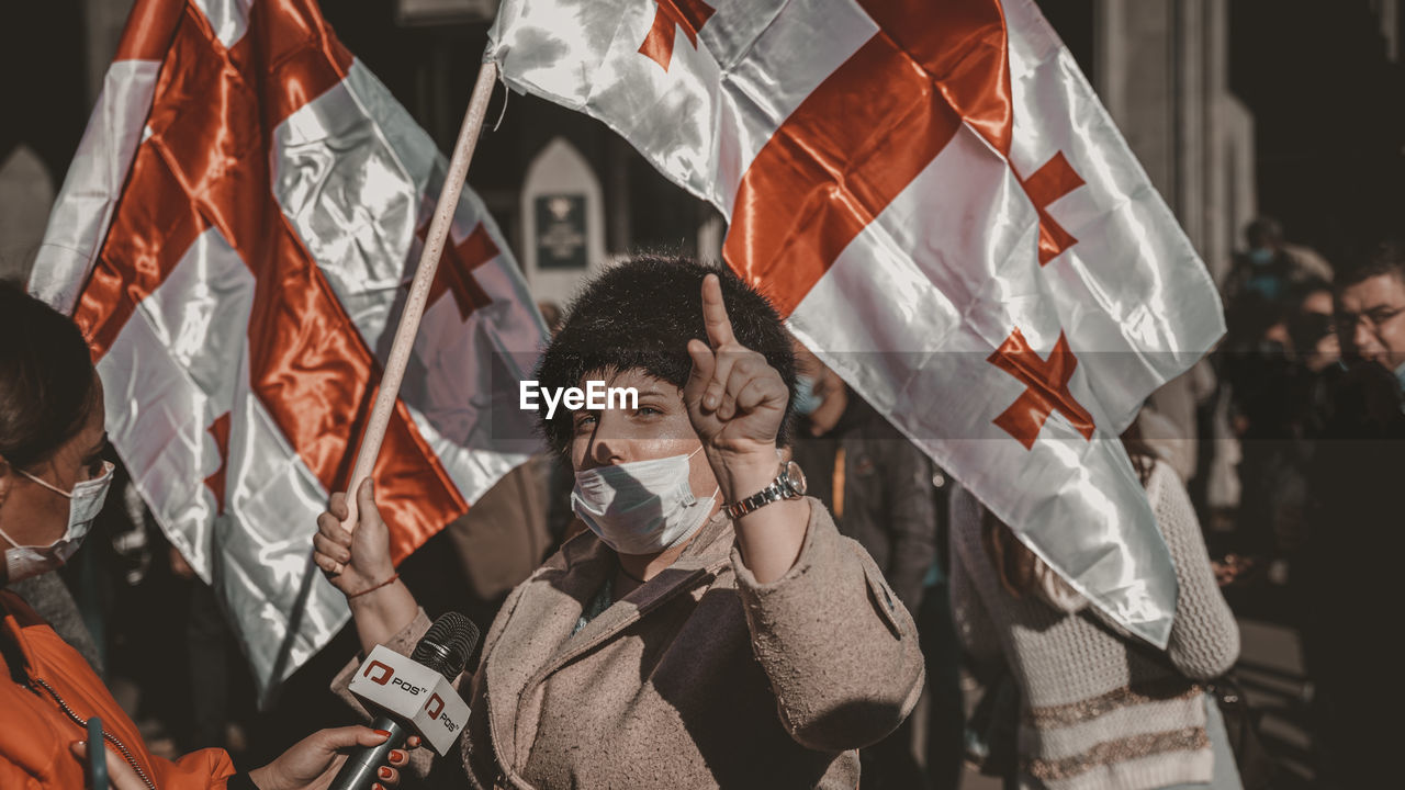 LOW ANGLE VIEW OF WOMAN HOLDING FLAG