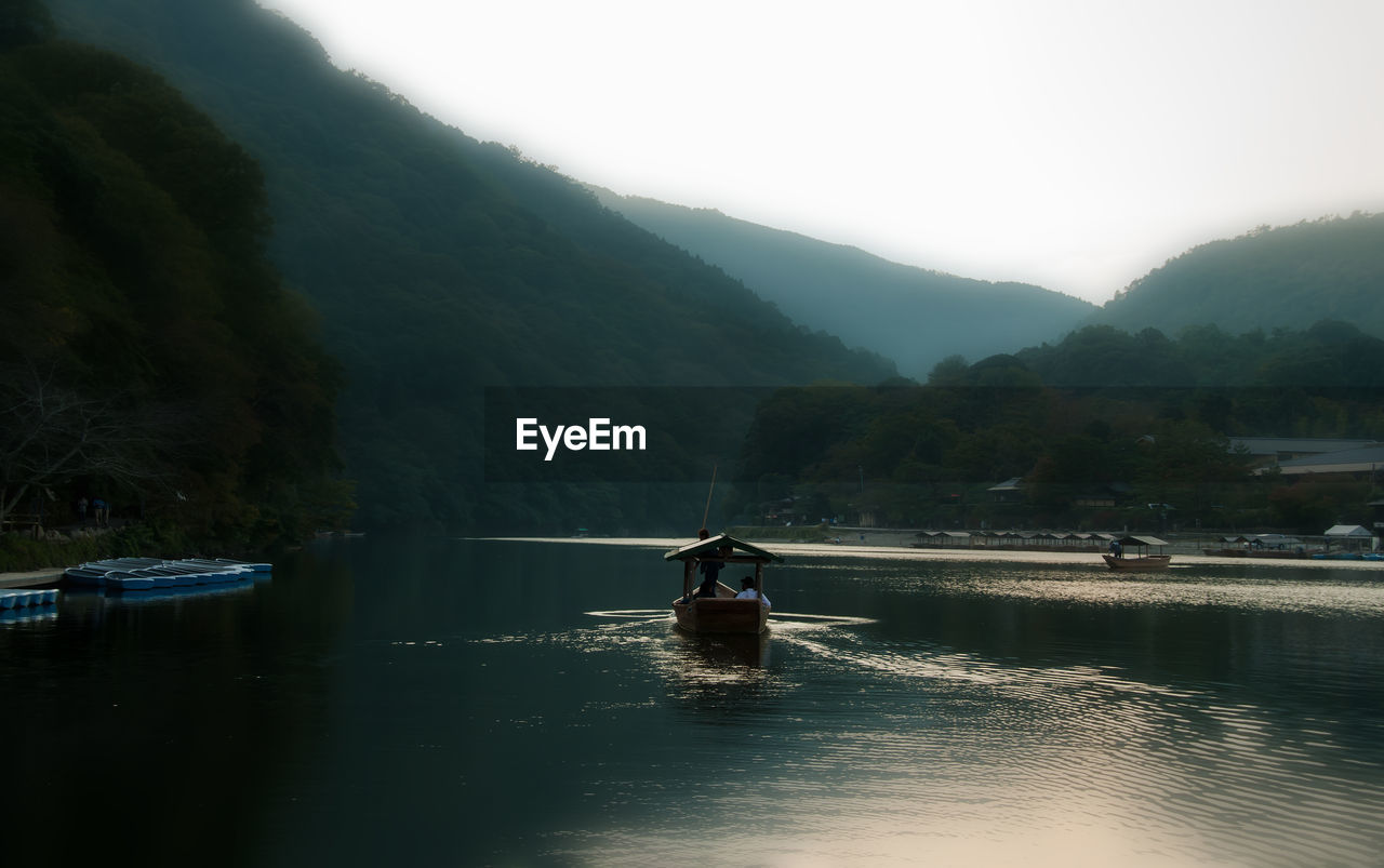 Boat sailing in river against mountains