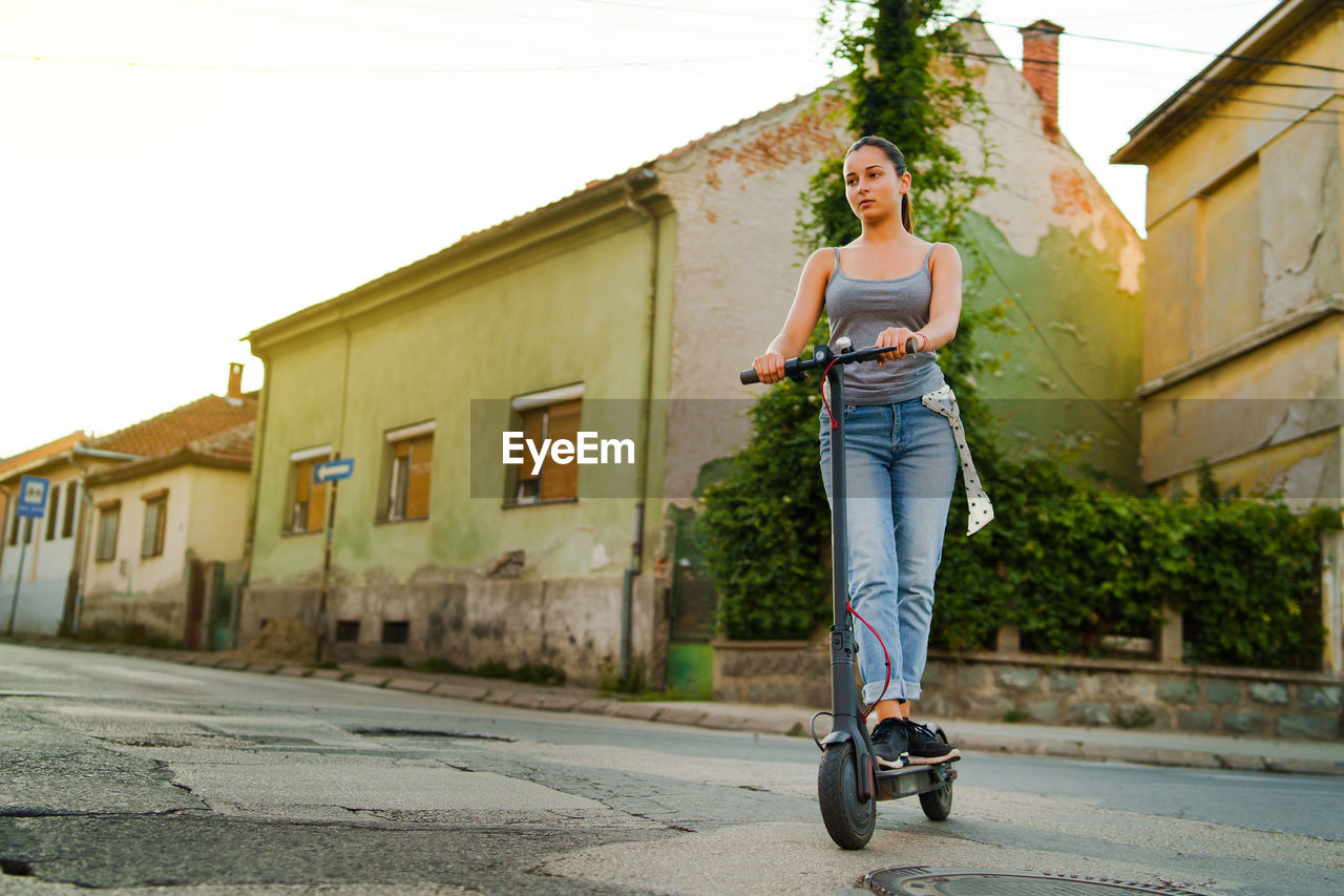 Woman riding motorcycle on street against building