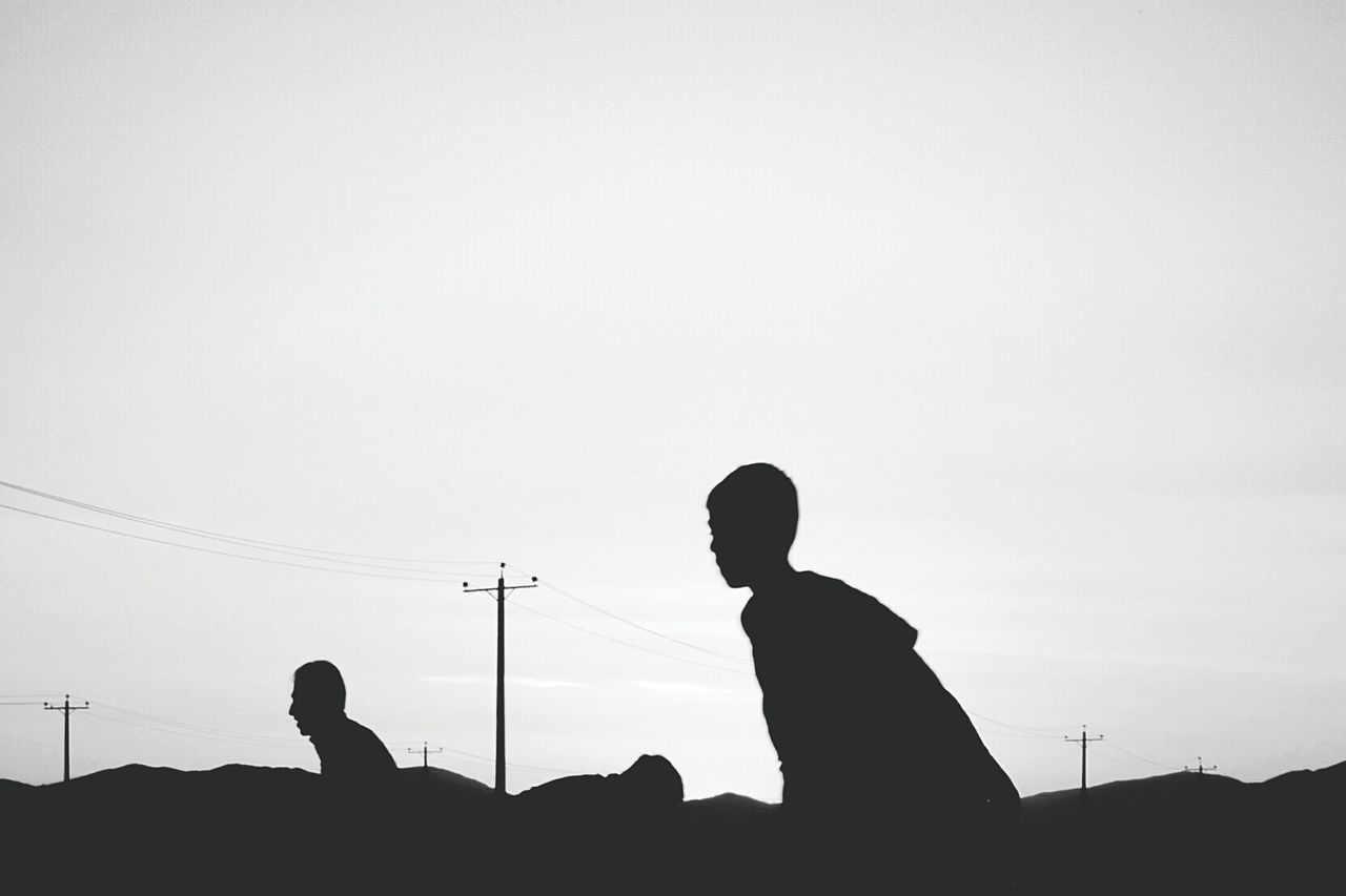 Silhouette people on landscape against clear sky