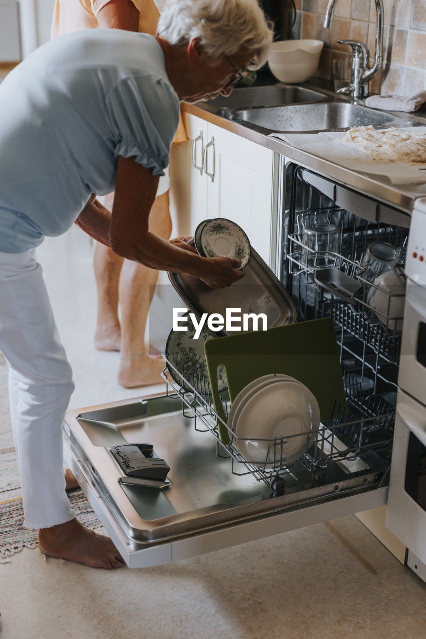 Senior woman putting dishes in dishwasher