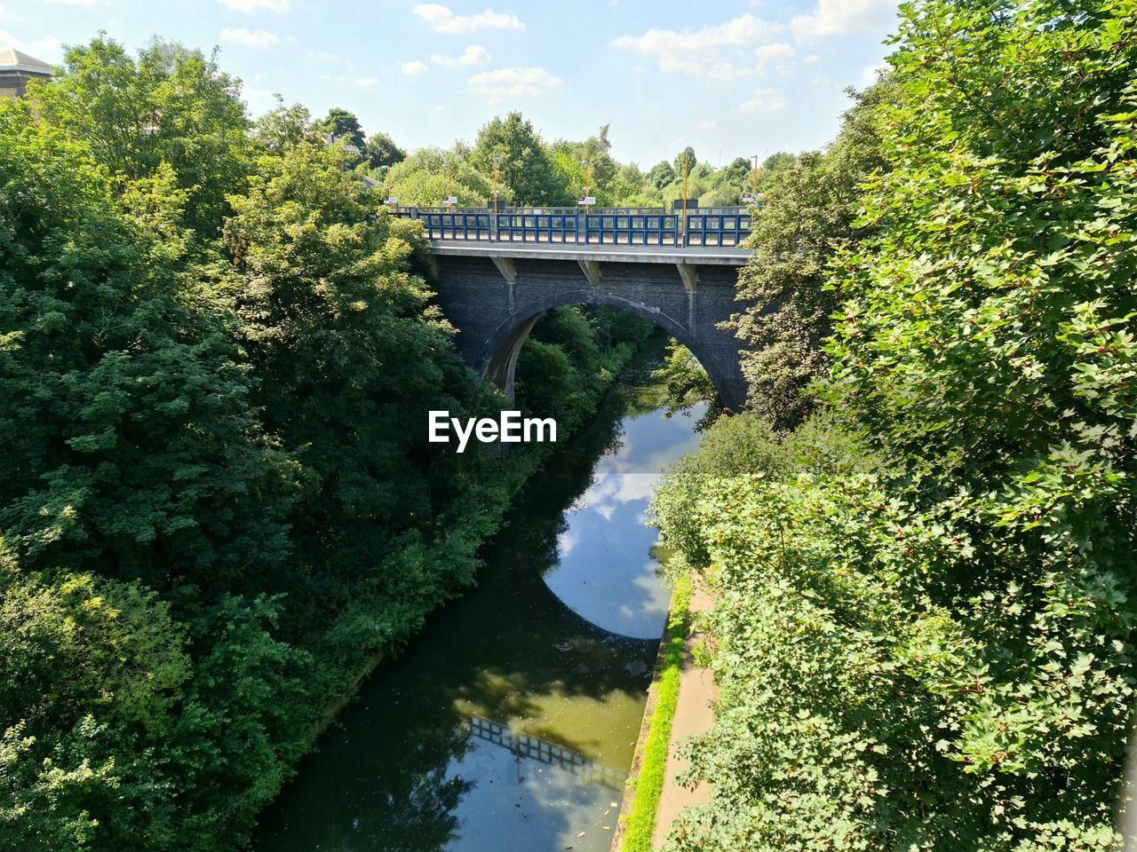 ARCH BRIDGE OVER RIVER AMIDST TREES AGAINST SKY