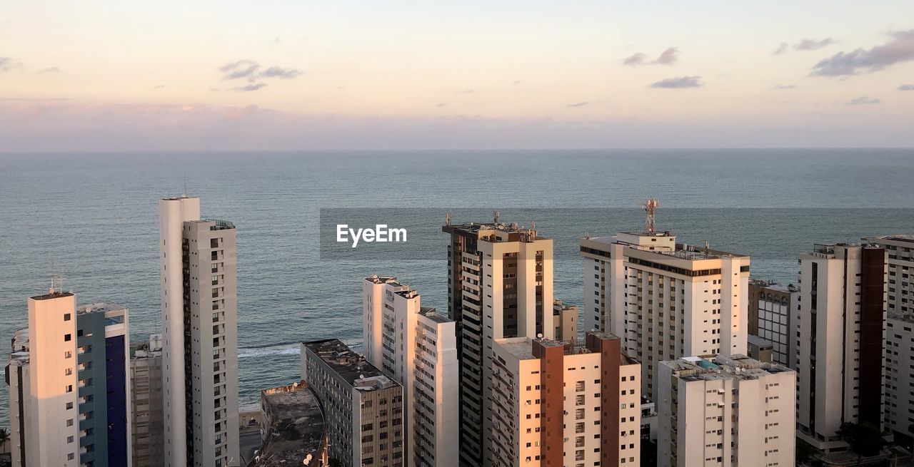 High angle view of buildings by sea against sky during sunset