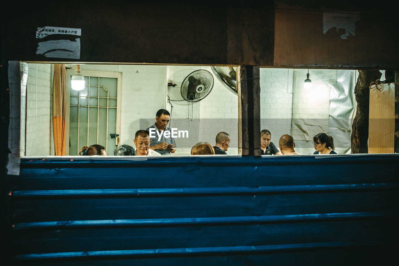 GROUP OF PEOPLE SITTING IN ILLUMINATED ROOM