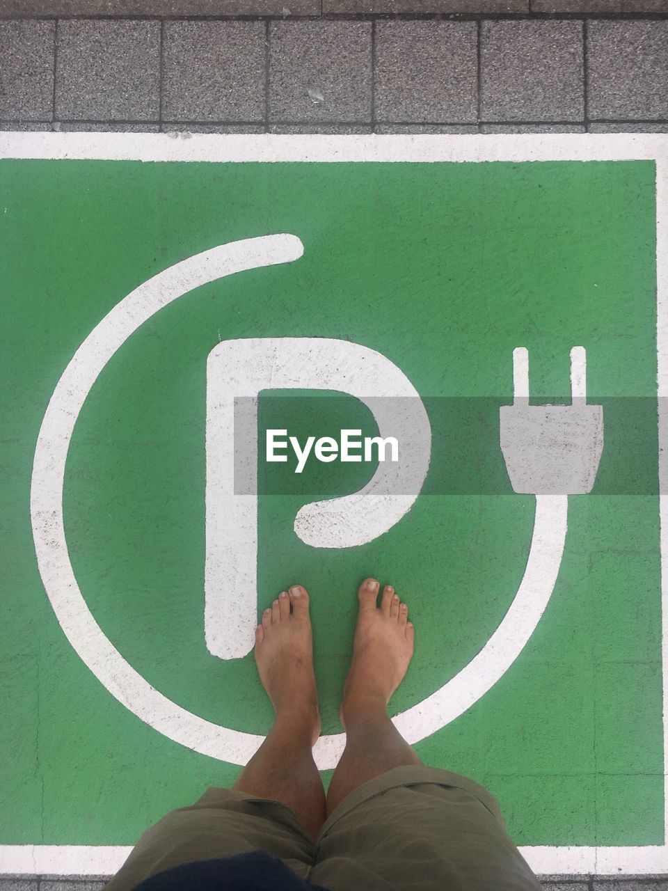 Low section of man standing on footpath sign