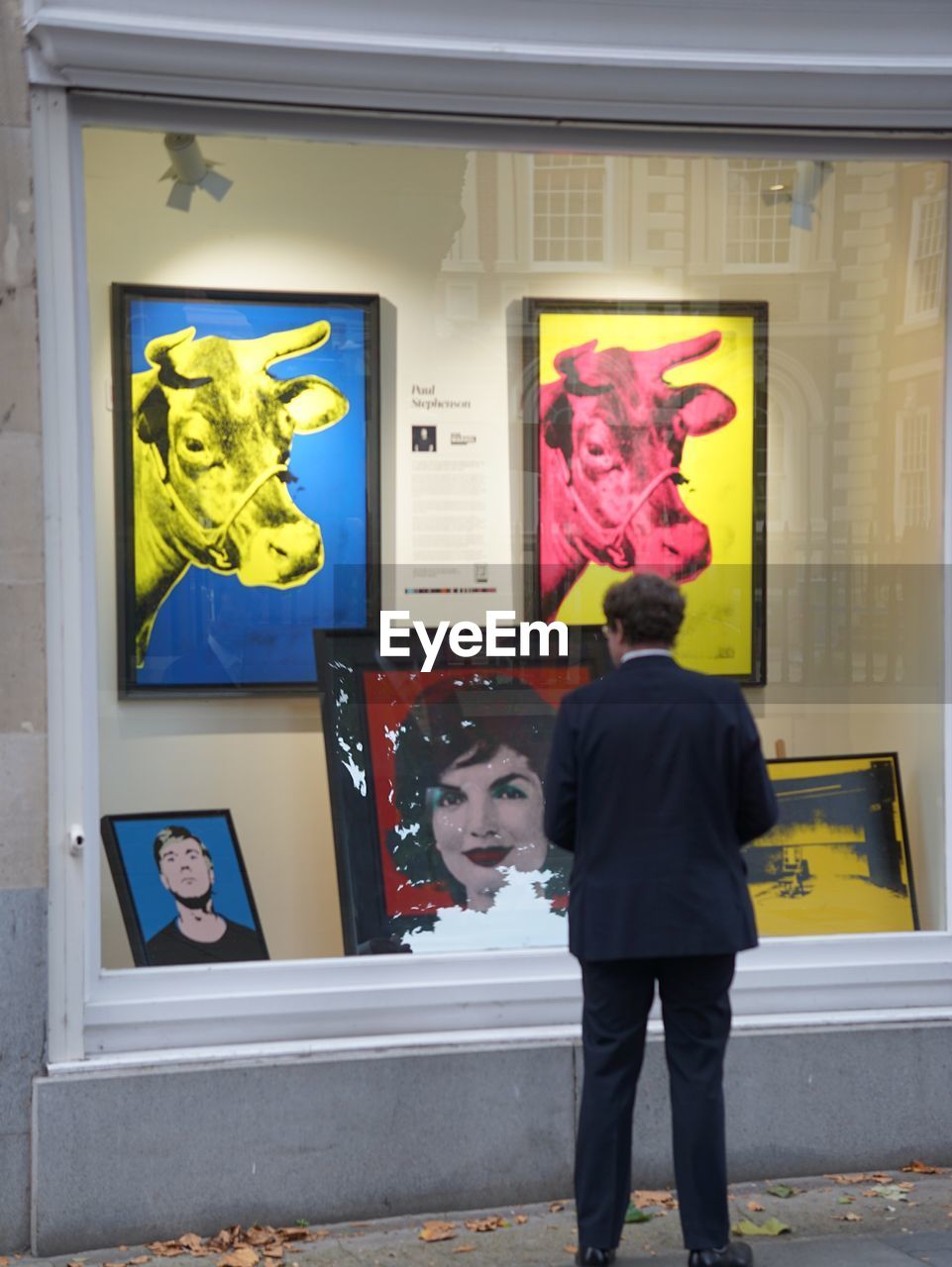 REAR VIEW OF MAN STANDING BY WINDOW IN A BUILDING