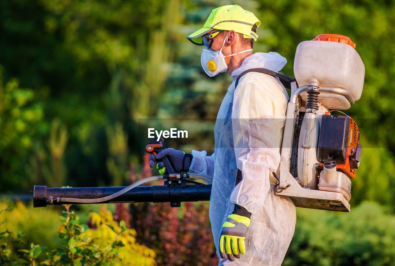 Side view of farm worker spraying pesticide