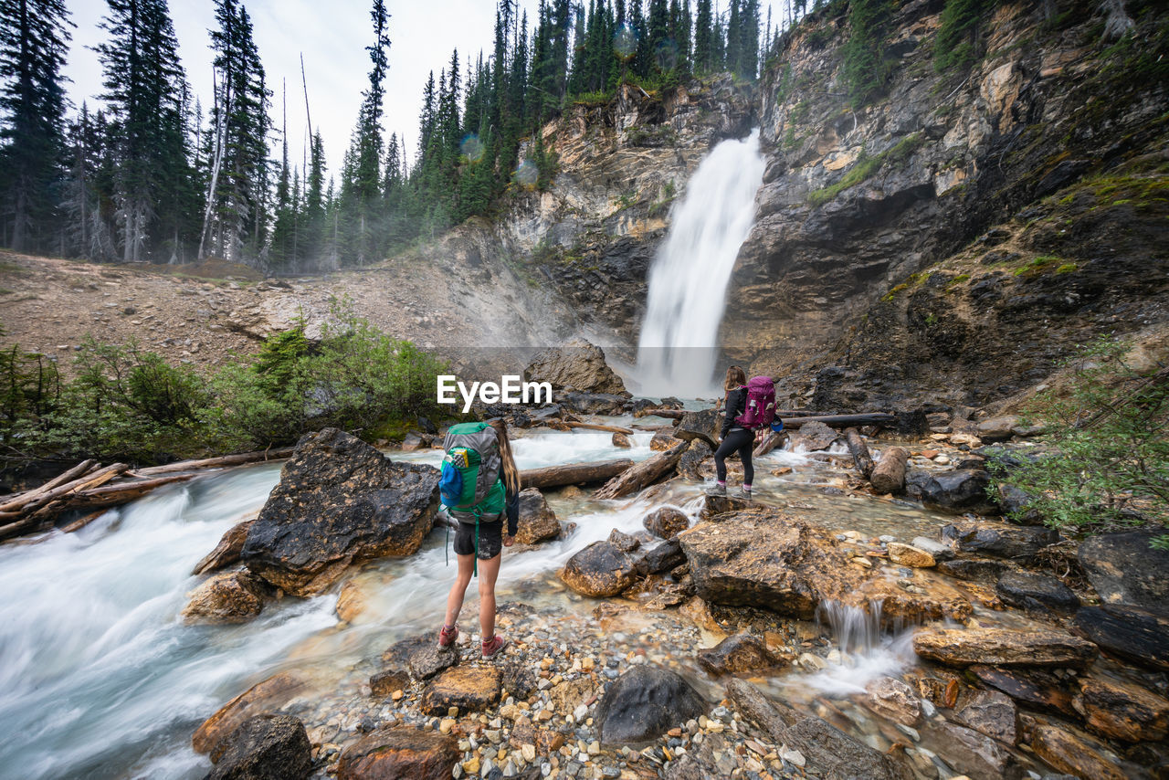 Backpackers admire laughing falls waterfall in yoho national park