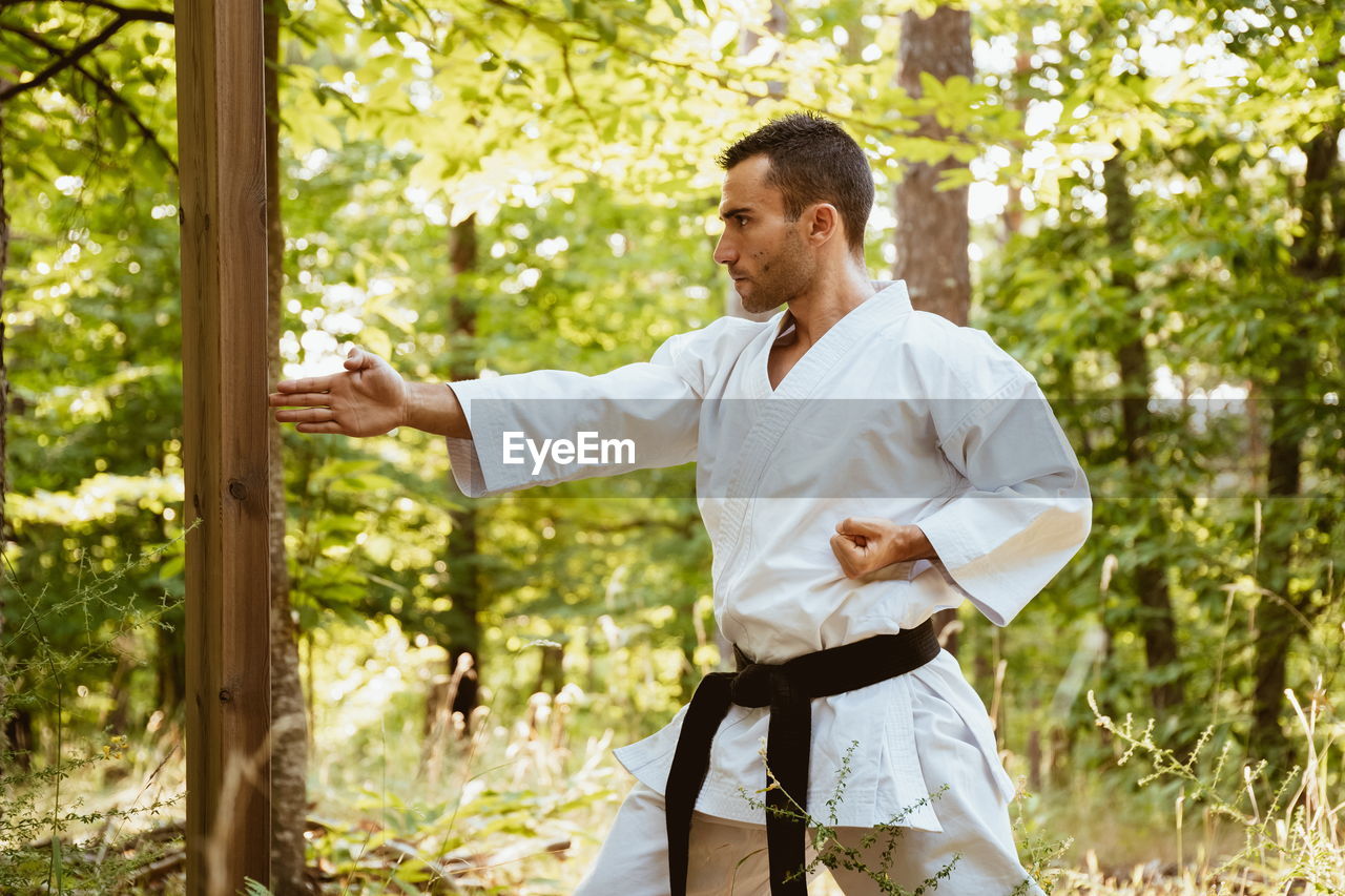 Man with karategi practicing martial arts in the forest