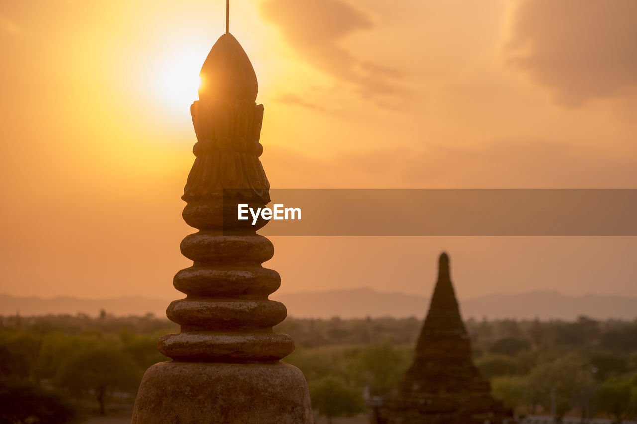 Steeple of historic temple against sky during sunset