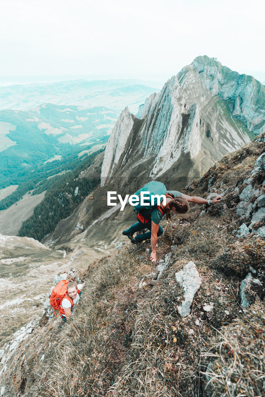 Two young women climbing steep terrain in front of steep mountains