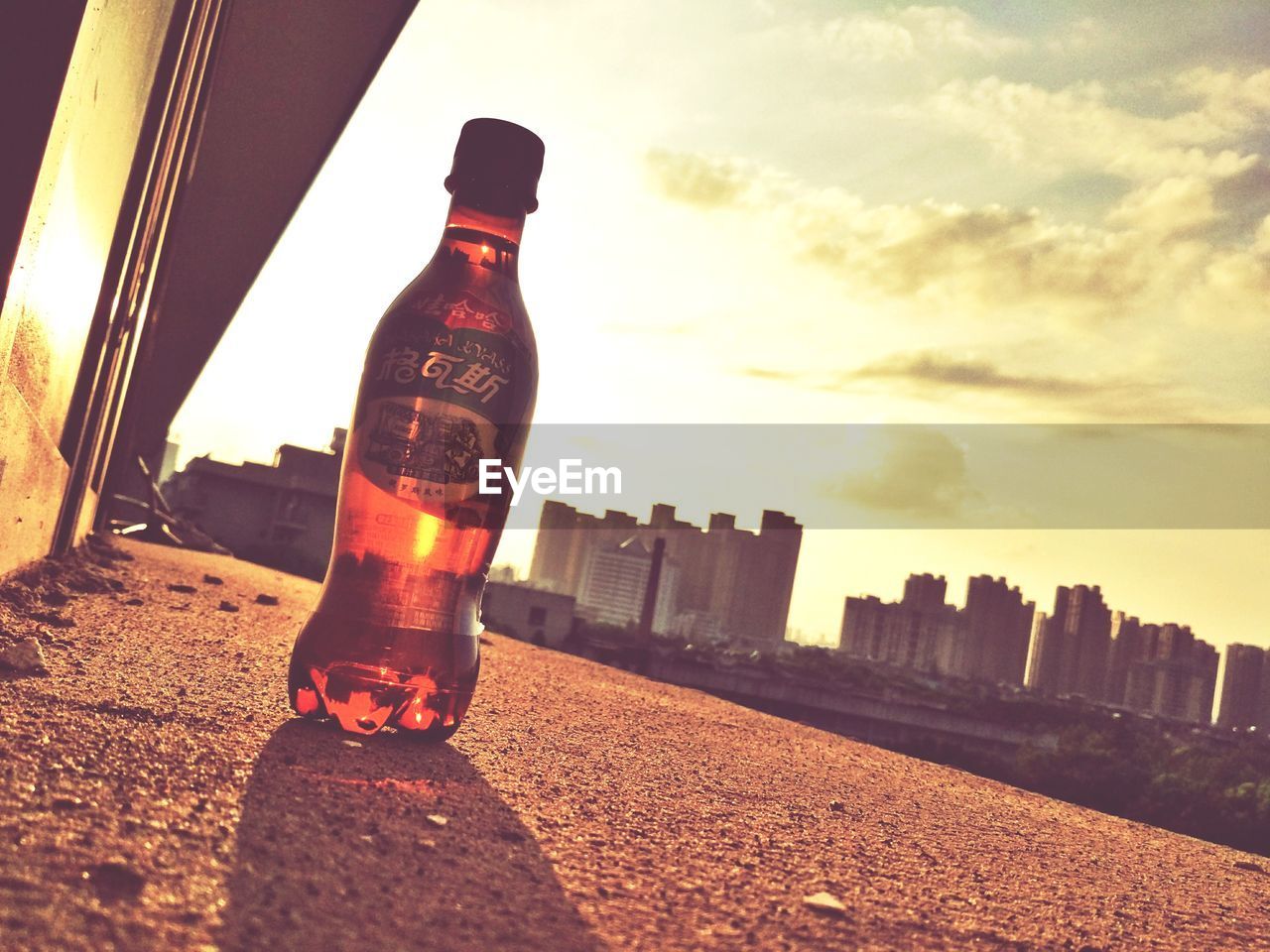 CLOSE-UP OF BOTTLE AGAINST CITYSCAPE