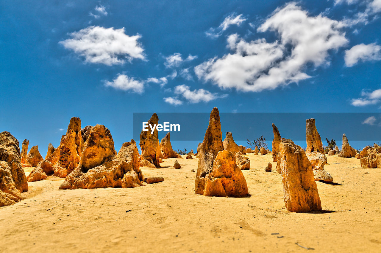 Rock formations on sand blue sky