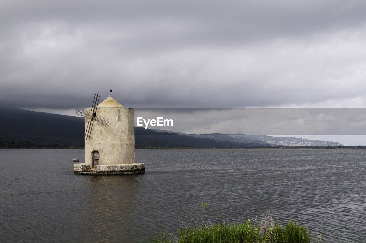 LIGHTHOUSE ON SEA BY BUILDING AGAINST SKY