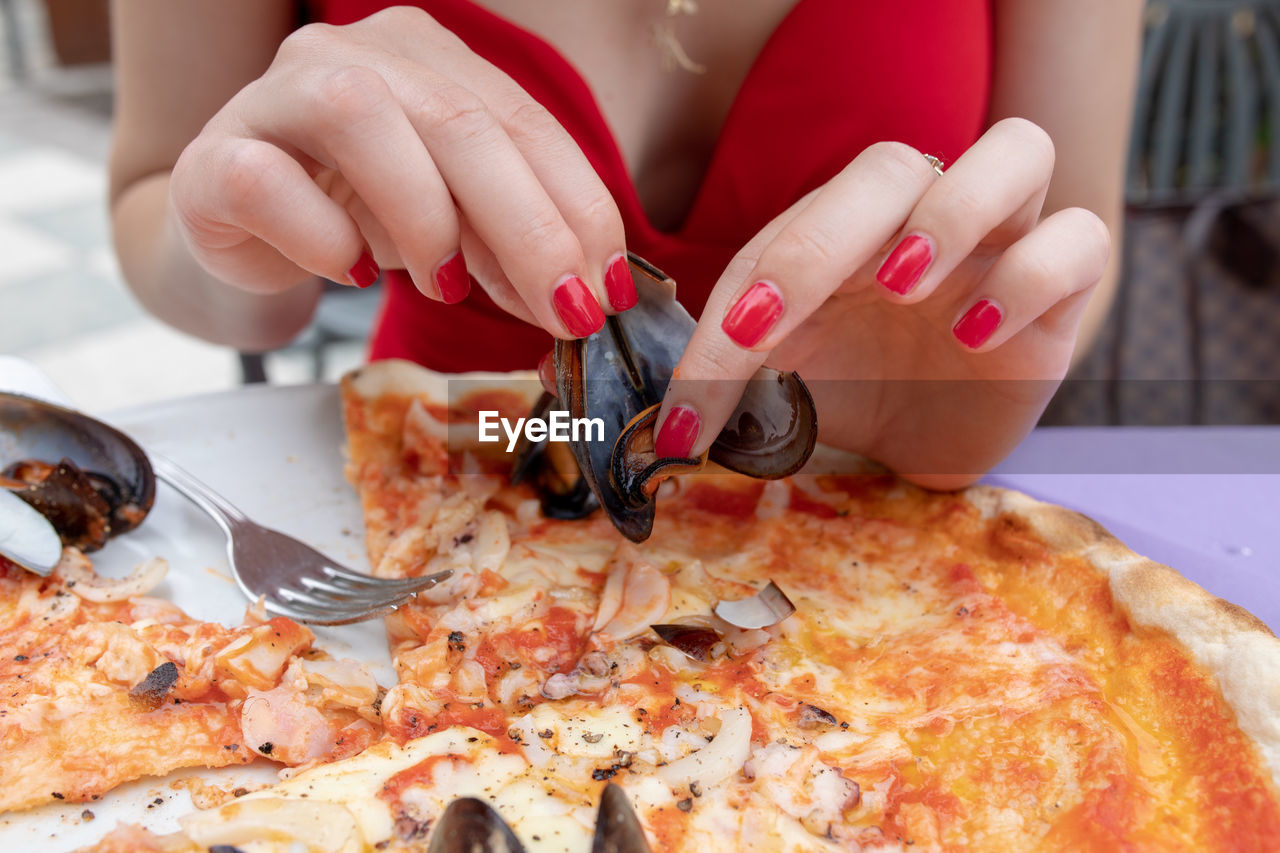 CLOSE-UP OF WOMAN HAND HOLDING PIZZA