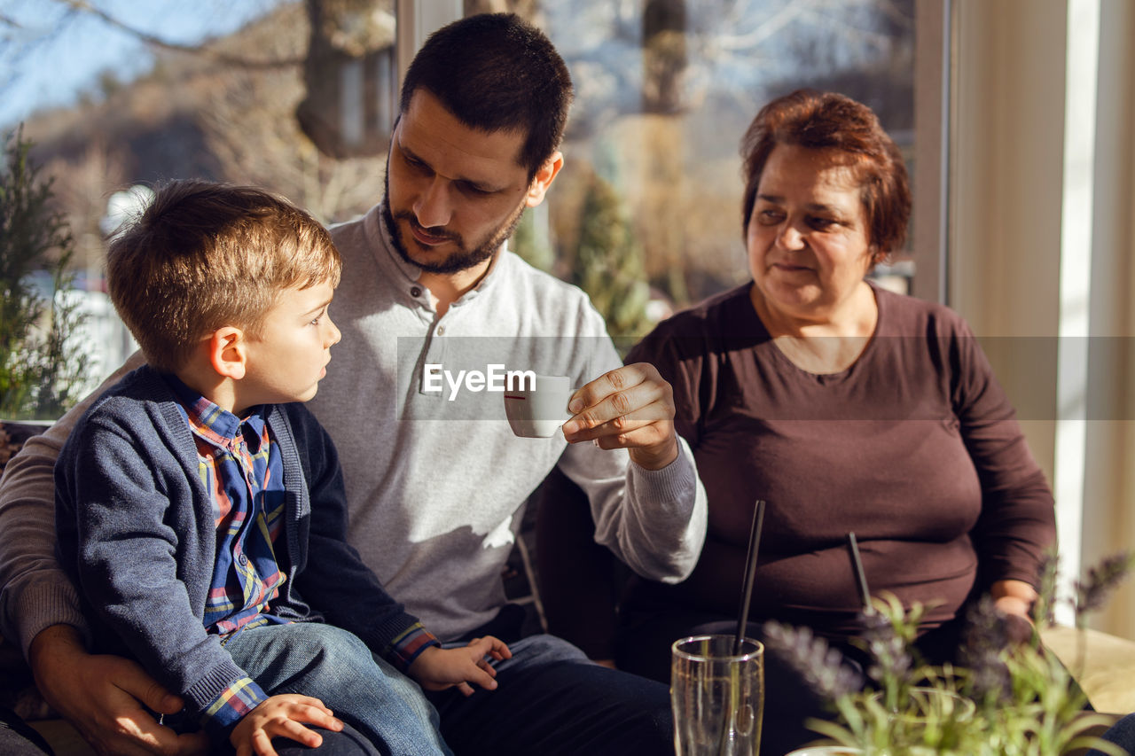 Father looking at son while sitting with mother at home