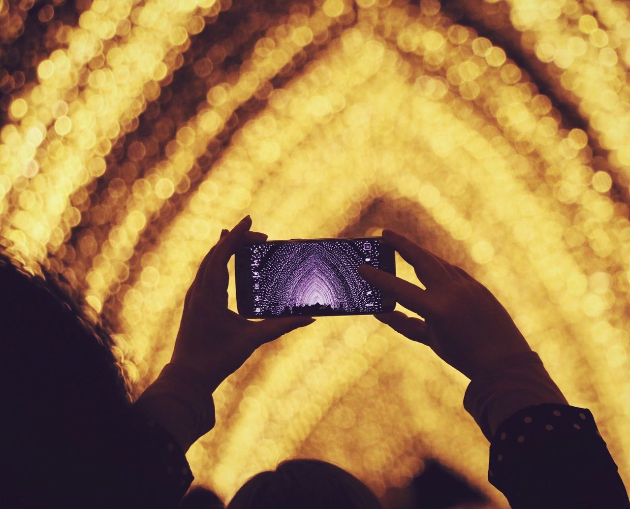 Person photographing illuminated cathedral of light at night