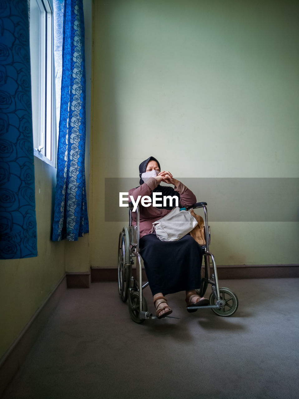 Portrait of a senior woman wearing hijab on wheelchair in a hospital.