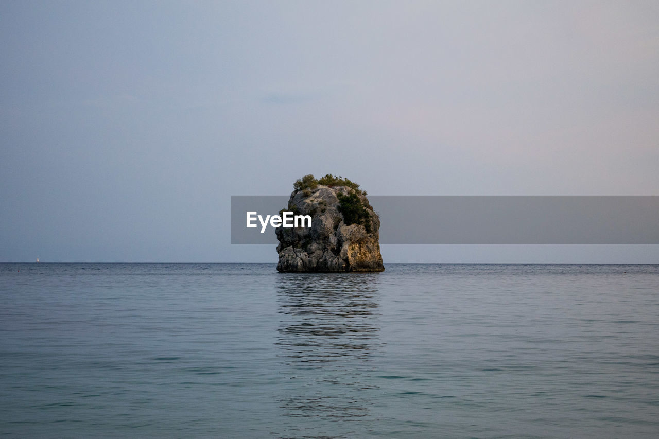 Rock formation in sea against sky