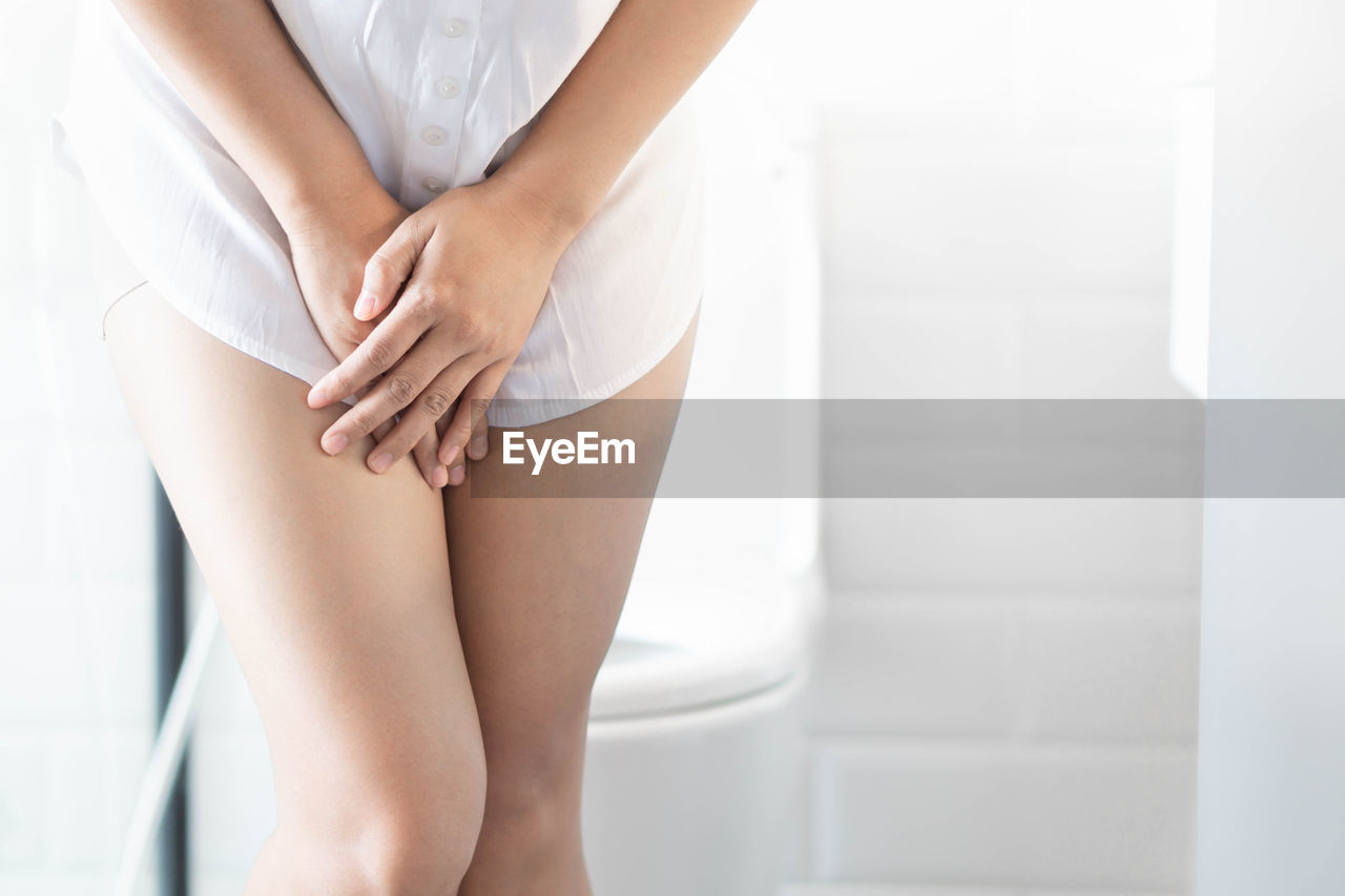 Midsection of woman suffering from urine infection in bathroom