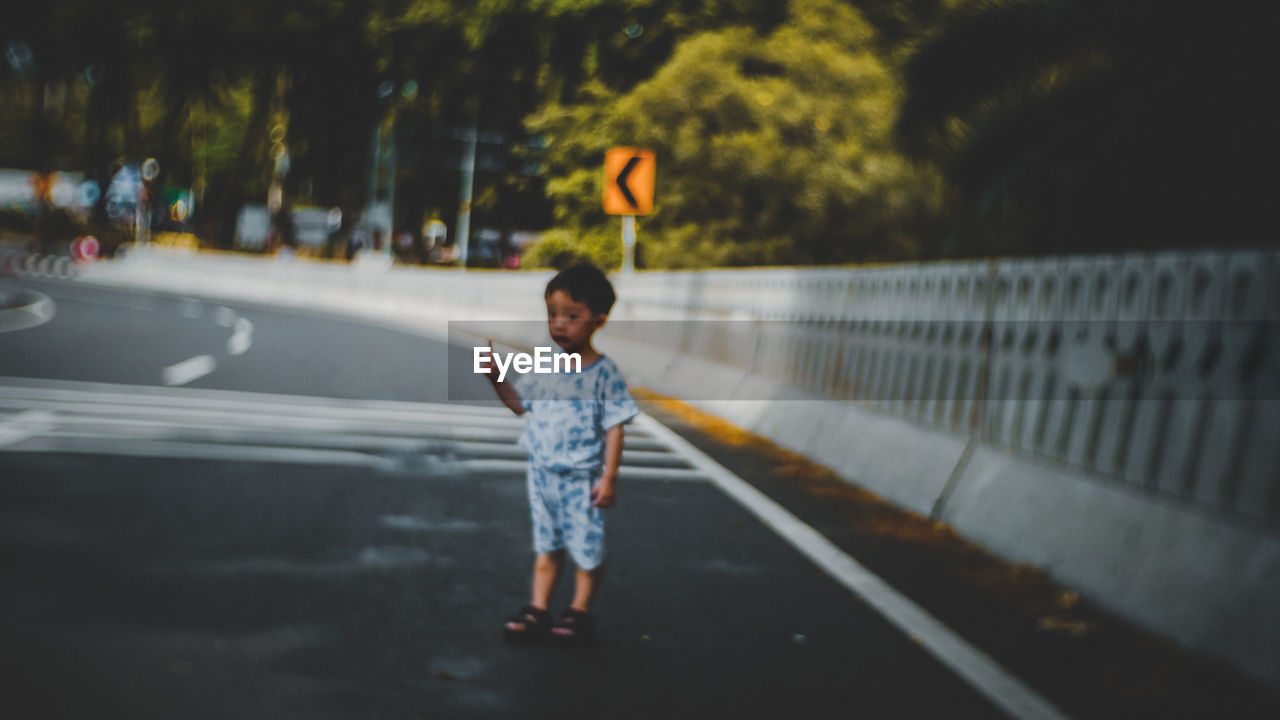 FULL LENGTH OF BOY STANDING BY ROAD